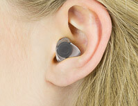 Gelber Gehörschutz im Ohr einer Frau.