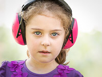 Mädchen mit rosa Kapselgehörschutz auf den Ohren.