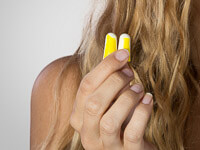 Eine Frau hält zwei gelbe Ohrstöpsel in der Hand