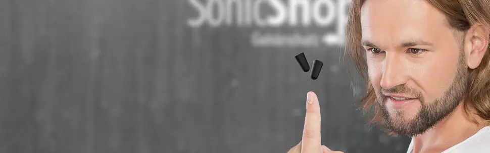 Mann balanciert schwarze Gehörschutzstöpsel über dem Zeigefinger, Firmenlogo im Hintergrund
