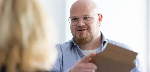 Ein Mann hält einen Karton in der Hand und unterhält sich mit einer Frau
